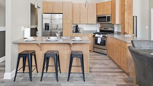 Eine moderne Küche mit Holzschränken, Edelstahlgeräten und einer zentralen Kochinsel mit Hockern.