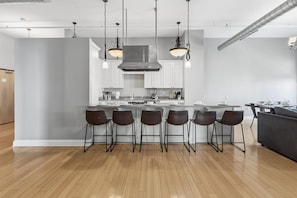 A modern kitchen with a central island, bar stools, and pendant lighting.