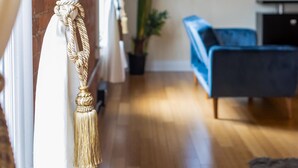A living room with a blue sofa, a TV, a potted plant, and a wooden floor. - Top Floor Loft in Downtown Indianapolis!!! (Indianapolis)