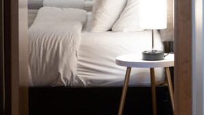 A bedroom with a bed, pillows, a bedside table with a lamp, and a wooden floor. - Top Floor Loft in Downtown Indianapolis!!! (Indianapolis)