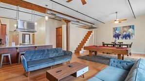 A modern living room with a sofa, coffee table, and pool table. - Top Floor Loft in Downtown Indianapolis!!! (Indianapolis)