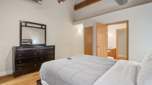 A bedroom with a bed, dresser, mirror, and wooden doors. - Top Floor Loft in Downtown Indianapolis!!! (Indianapolis)