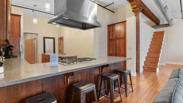 A modern kitchen with a central island, wooden cabinets, and a staircase leading to another level. - Top Floor Loft in Downtown Indianapolis!!! (Indianapolis)