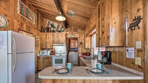 A rustic kitchen with wooden walls, a central island, and various appliances including a refrigerator, stove, and microwave. - Quiet Retreat w/ Hot Tub - 16 Miles to Ski Apache! (Ruidoso)