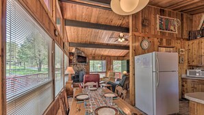 A wooden cabin interior with a dining table set for four, a refrigerator, and a kitchen area. - Quiet Retreat w/ Hot Tub - 16 Miles to Ski Apache! (Ruidoso)
