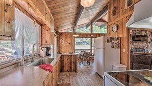 A wooden cabin interior with a kitchen, dining area, and a stone fireplace. - Quiet Retreat w/ Hot Tub - 16 Miles to Ski Apache! (Ruidoso)