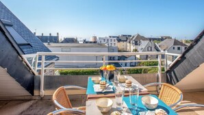 Terraço no telhado com mesa posta para refeições, com vista para a paisagem urbana.
