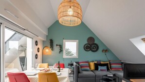 Um apartamento loft moderno com área de jantar, um sofá cinza com almofadas coloridas e uma janela grande.