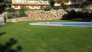 Zona residencial con piscina, muro de piedra y dos edificios de varios pisos con balcones.