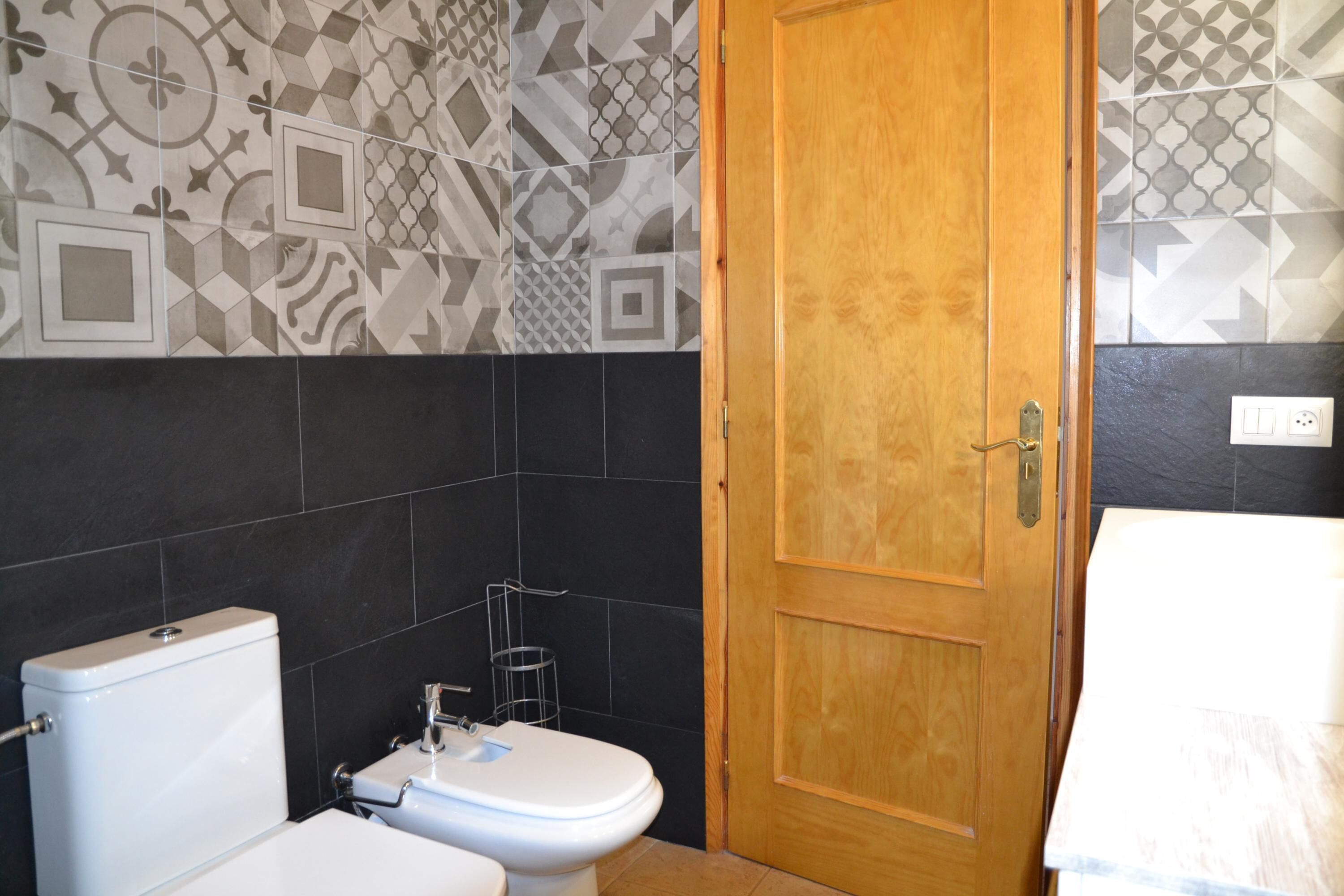 Een badkamer met toilet, wastafel en een houten deur.
