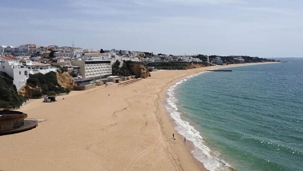 Ein Küstenstrand mit Gebäuden im Hintergrund.