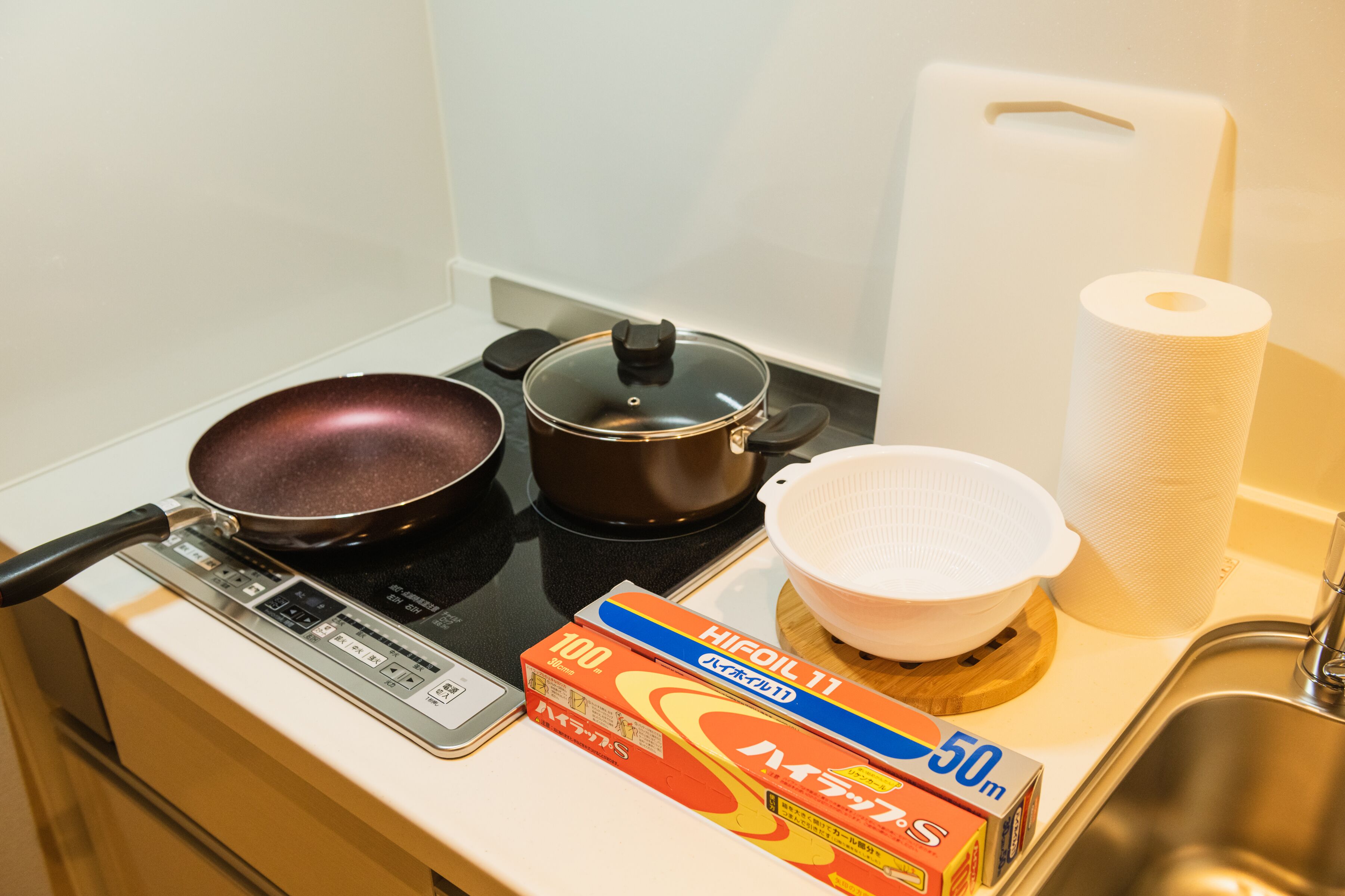 A kitchen with a stove, a frying pan, a pot, a colander, and a box of Hifool 11 oil.