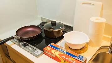 A kitchen with a stove, a frying pan, a pot, a colander, and a box of Hifool 11 oil.
