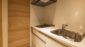 Une cuisine moderne dotée d’un évier en acier inoxydable, d’une cuisinière encastrée et d’une porte en bois.