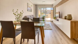 Un espai de vida modern amb zona de menjador, sofà i televisió.