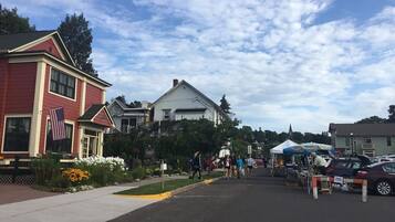 A street with houses, a sidewalk, and a market area with tents and people.