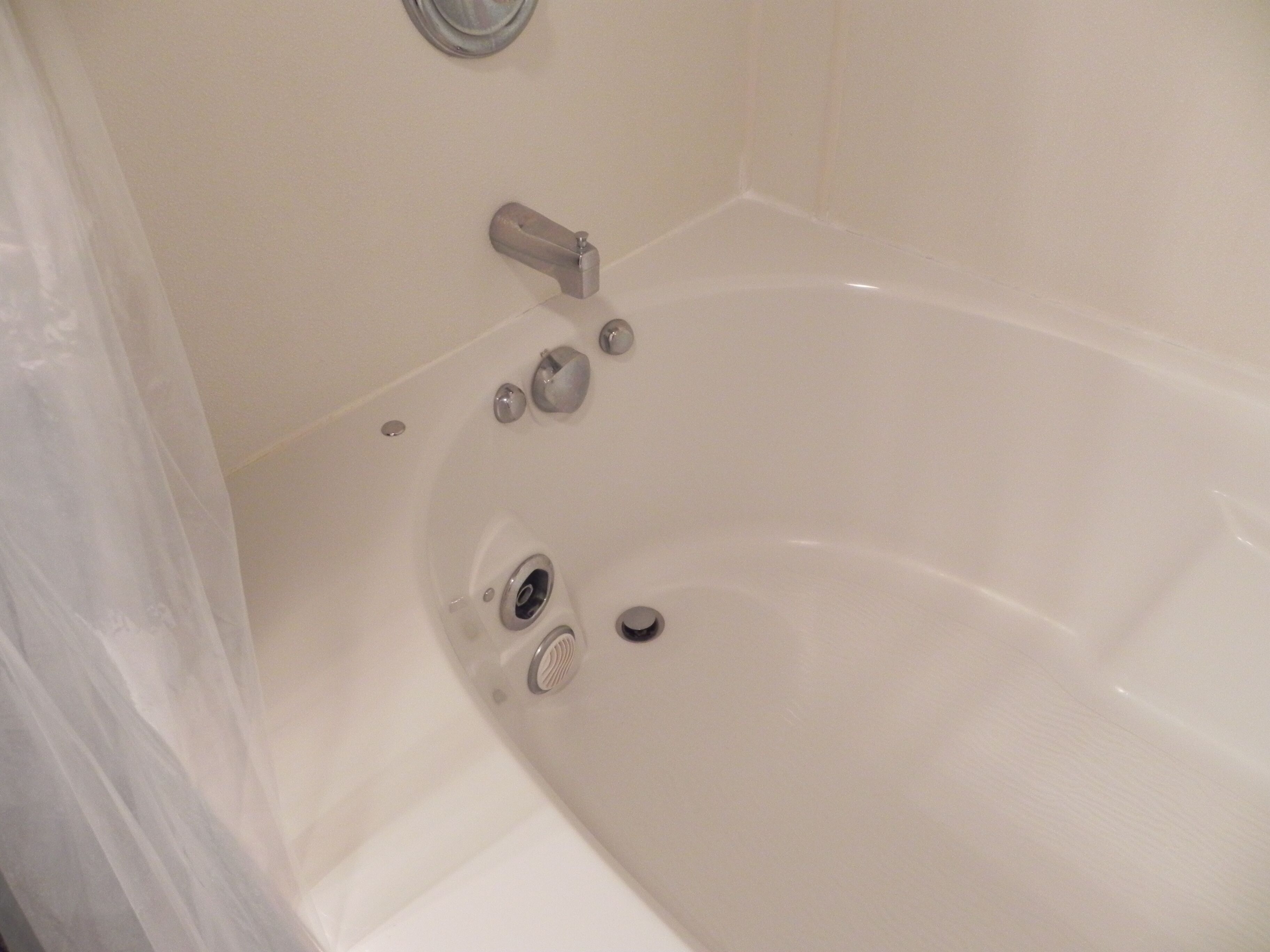A white bathtub with a faucet and a drain.