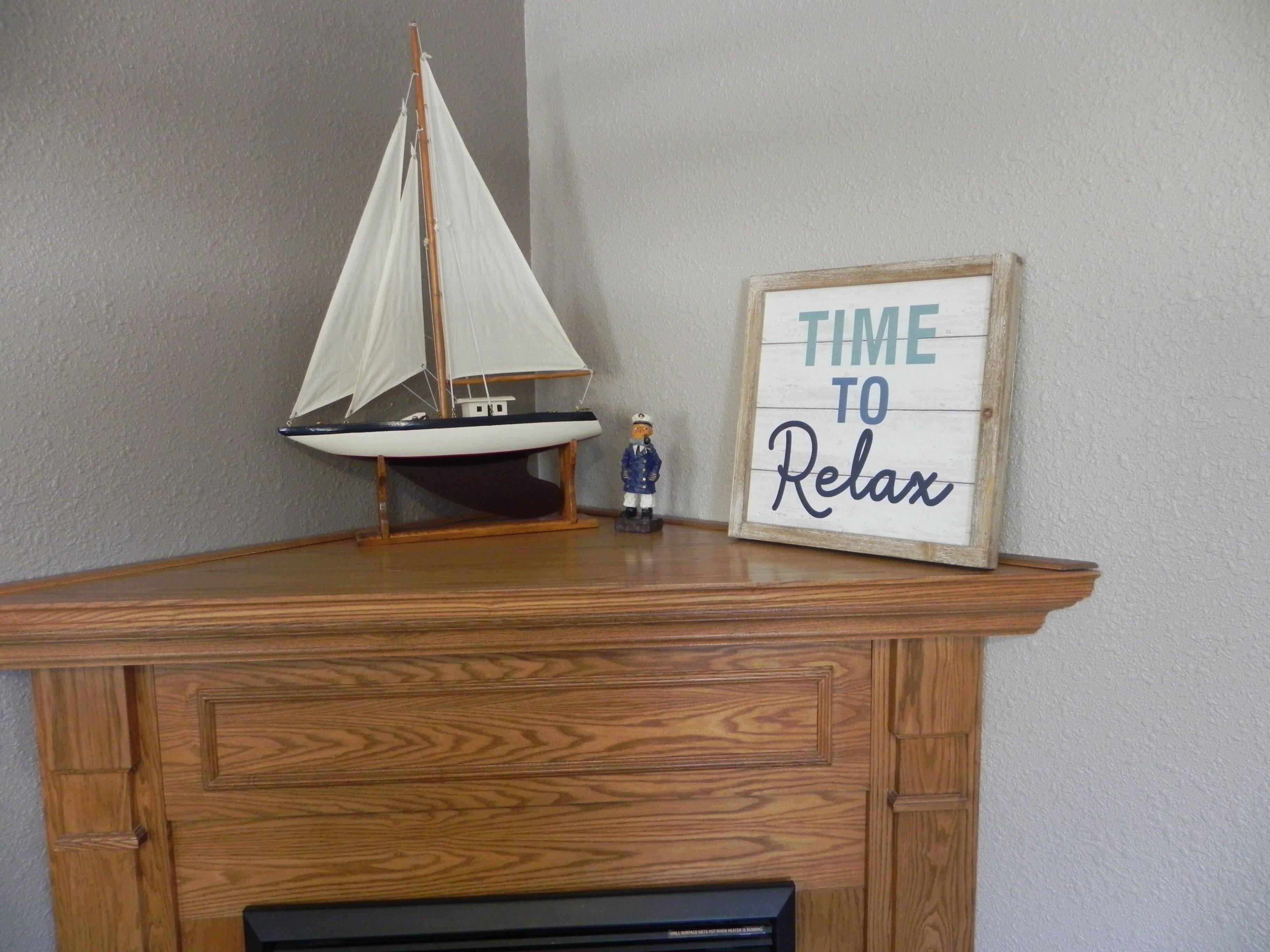A wooden desk with a model sailboat and a framed sign that reads "TIME TO RELAX".