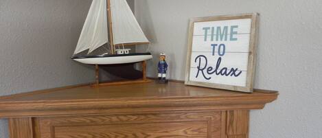 A wooden desk with a model sailboat and a framed sign that reads "TIME TO RELAX".