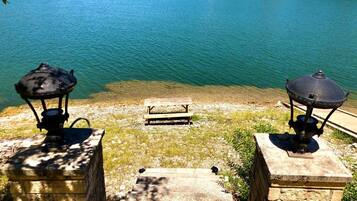 A stone staircase leading to a wooden bench by a lake with two lanterns on either side.