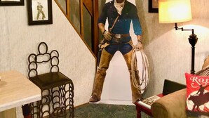 Quarto com escada de madeira, quadro na parede, luminária e uma estátua de cowboy.
