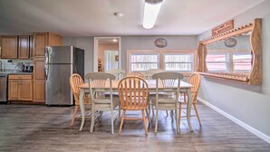 A kitchen with wooden cabinets, a stainless steel refrigerator, and a dining table with six chairs.