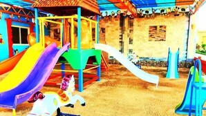 Une aire de jeux avec des toboggans colorés et une structure d’escalade en forme de cheval.