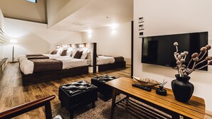 A modern hotel room with a loft bed, a flat-screen TV, a wooden desk, and a vase with dried flowers. - Yamahana Onsen Tondenyu Ryokan (Sapporo)