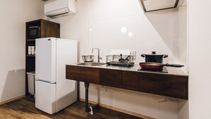 A compact kitchen with a white refrigerator, wooden cabinets, a sink, and a stove. - Yamahana Onsen Tondenyu Ryokan (Sapporo)