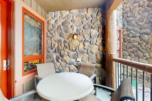 Relax in this serene outdoor seating area with a round table and two chairs, set against a stone wall.