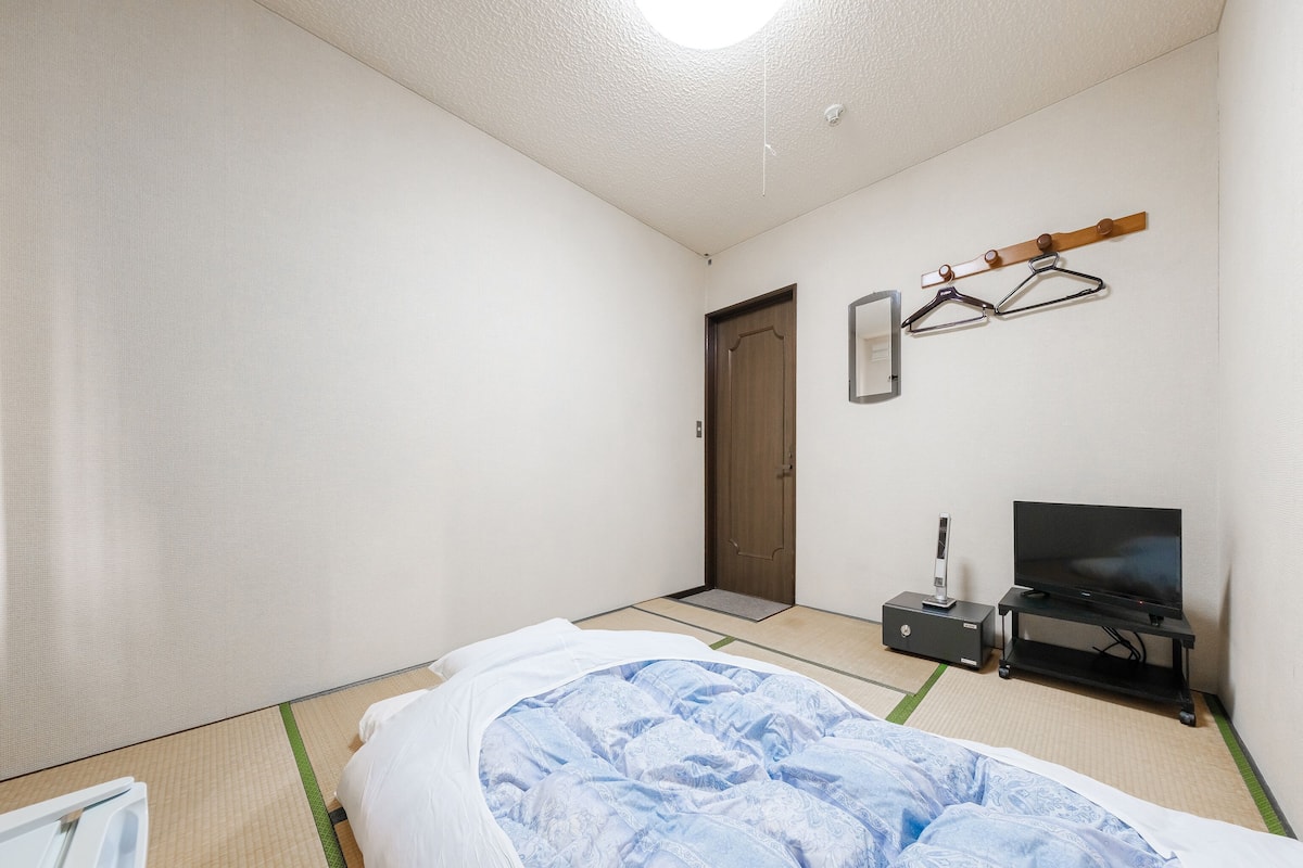 Une chambre à coucher avec un lit, une télévision et une étagère en bois avec des cintres.