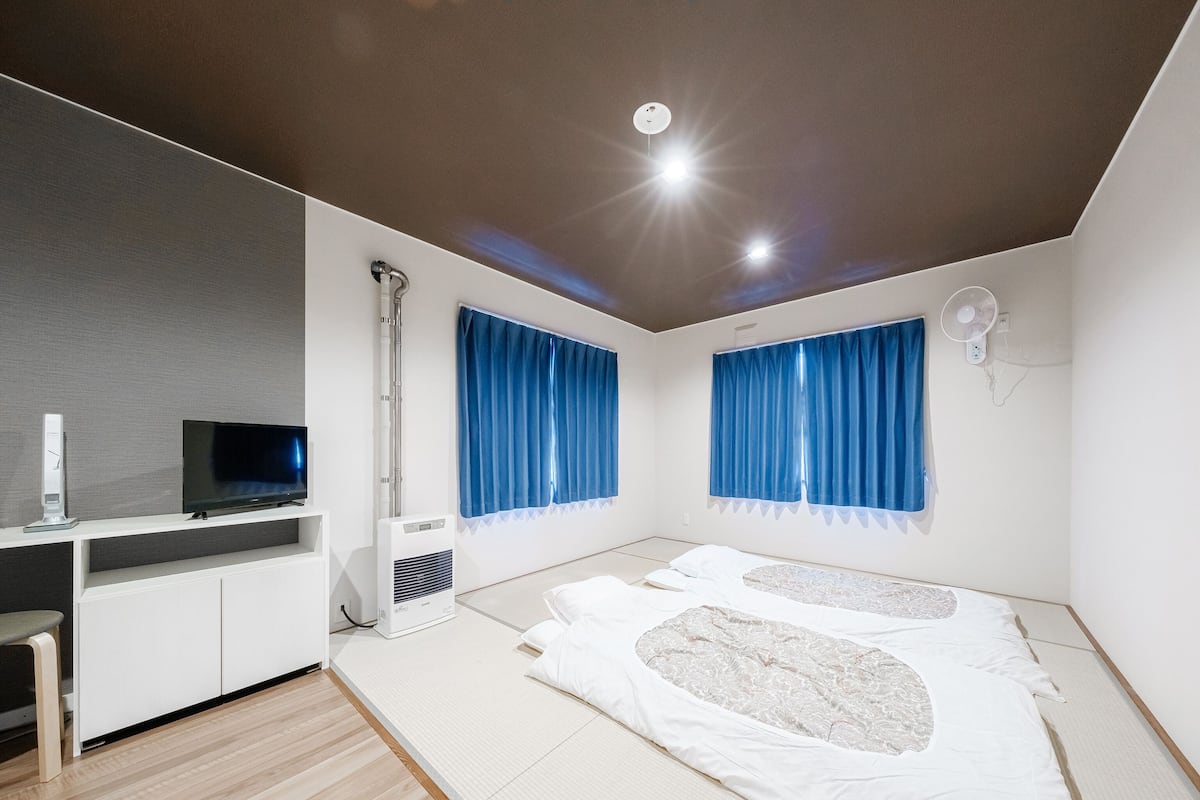 Une chambre moderne équipée d’un lit, d’une télévision, d’un radiateur et d’un ventilateur.