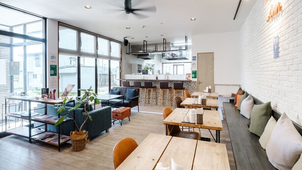 Un café moderne doté d’un espace cuisine, de tables en bois et de sièges confortables.