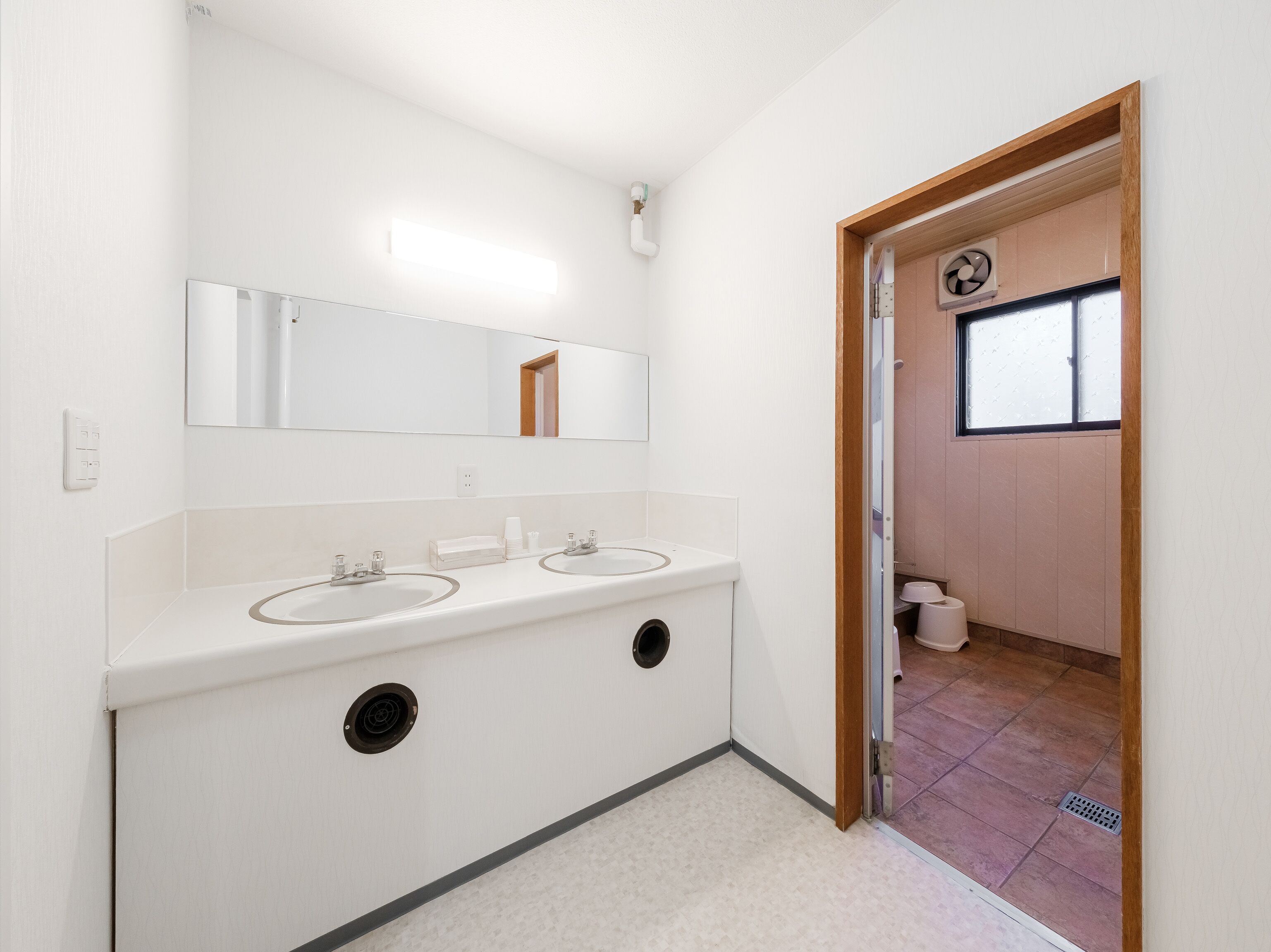 Un baño con dos lavamanos, un espejo y una ventana.