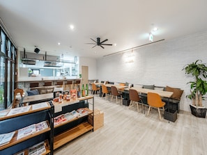 Un comedor moderno con mesas y sillas de madera, un ventilador de techo y una pared de ladrillo.