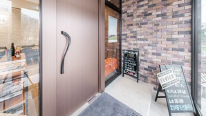 Un intérieur moderne avec une porte en bois, un mur en briques et une porte vitrée donnant sur un espace détente.