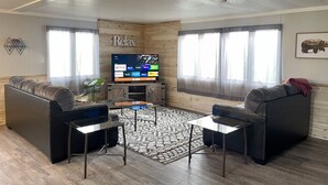 Una sala de estar acogedora con un televisor de pantalla plana, dos sofás, una mesa de centro y una alfombra estampada.