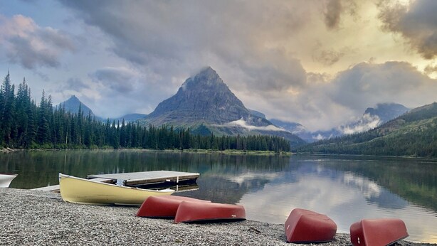 Un lago tranquilo con una montaña al fondo, rodeado de un bosque denso.