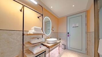 A modern bathroom with a vanity, a mirror, a towel rack, and a door.