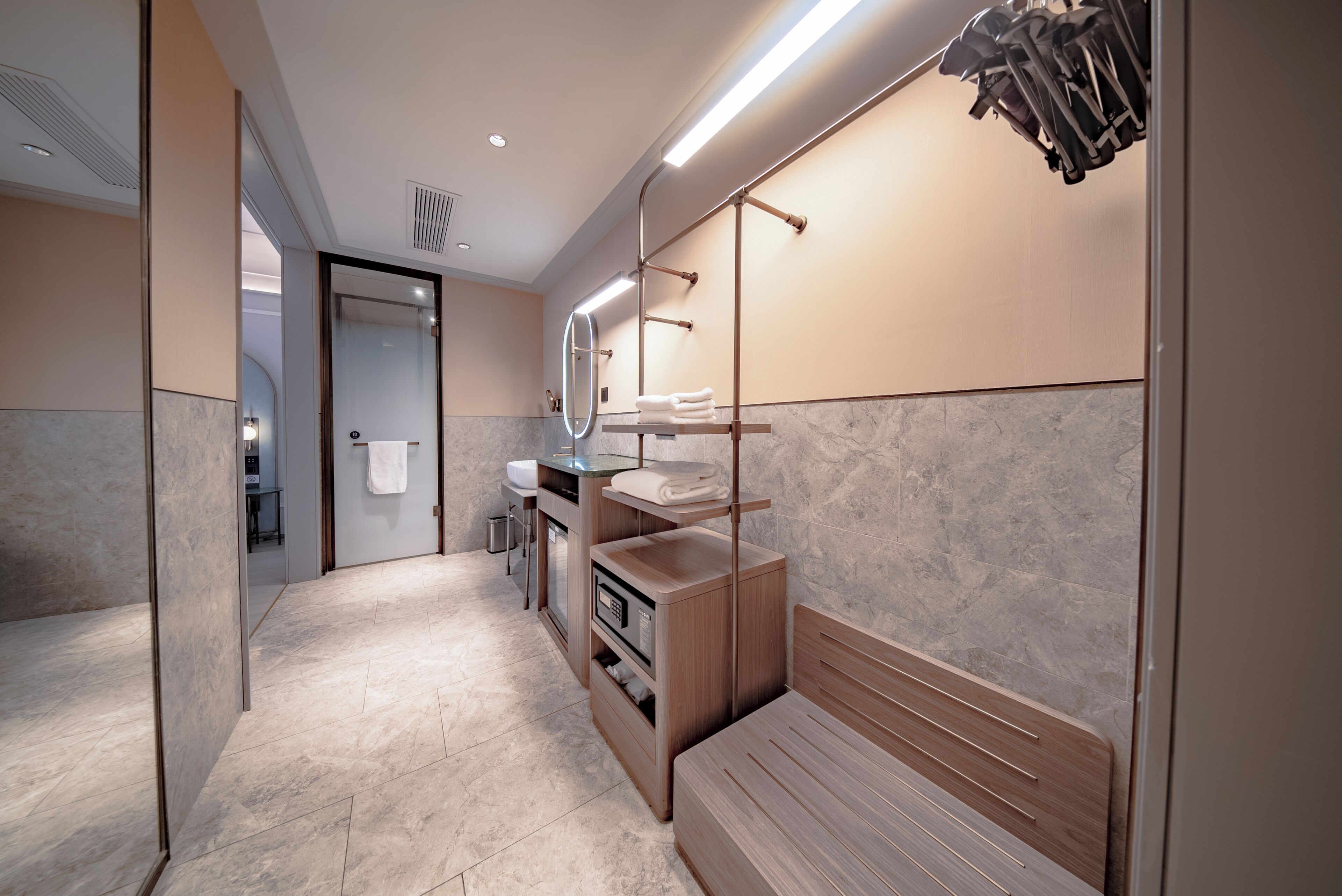 A modern bathroom with a vanity, mirror, towel rack, and a bench.