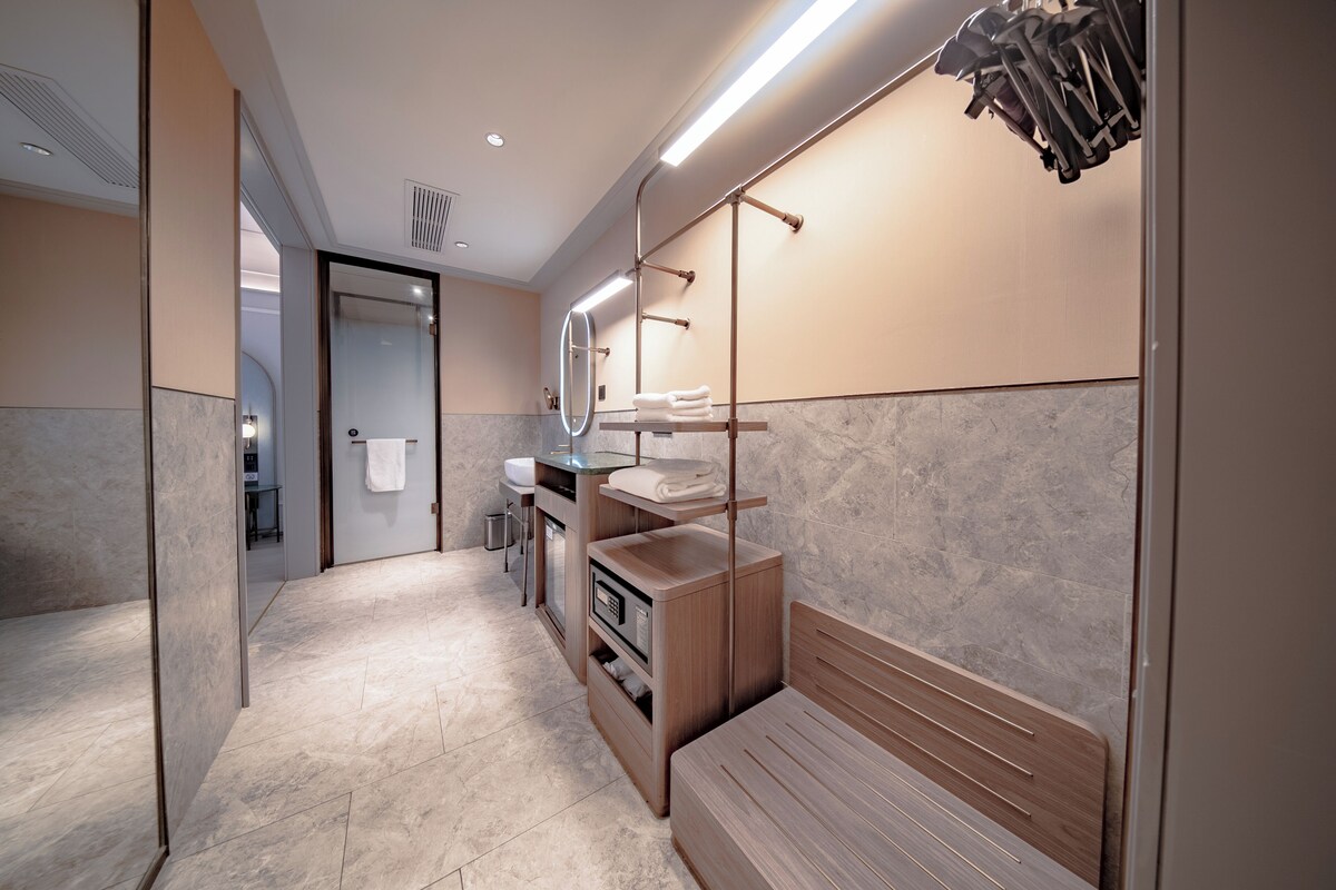 Un baño moderno con tocador, espejo, toallero y un banco.