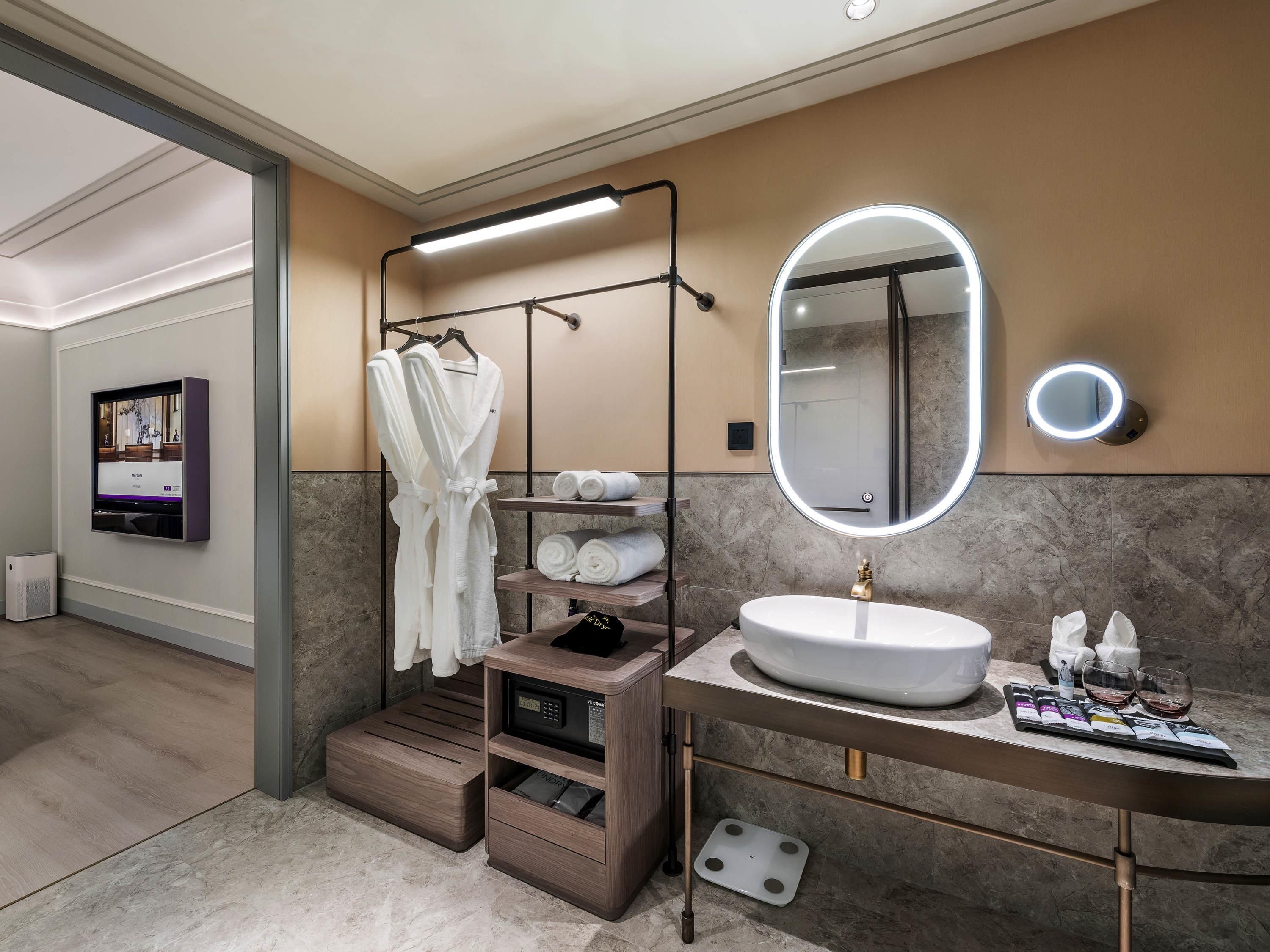Un baño moderno con tocador, un espejo grande, un perchero para bata y un perchero para toallas.