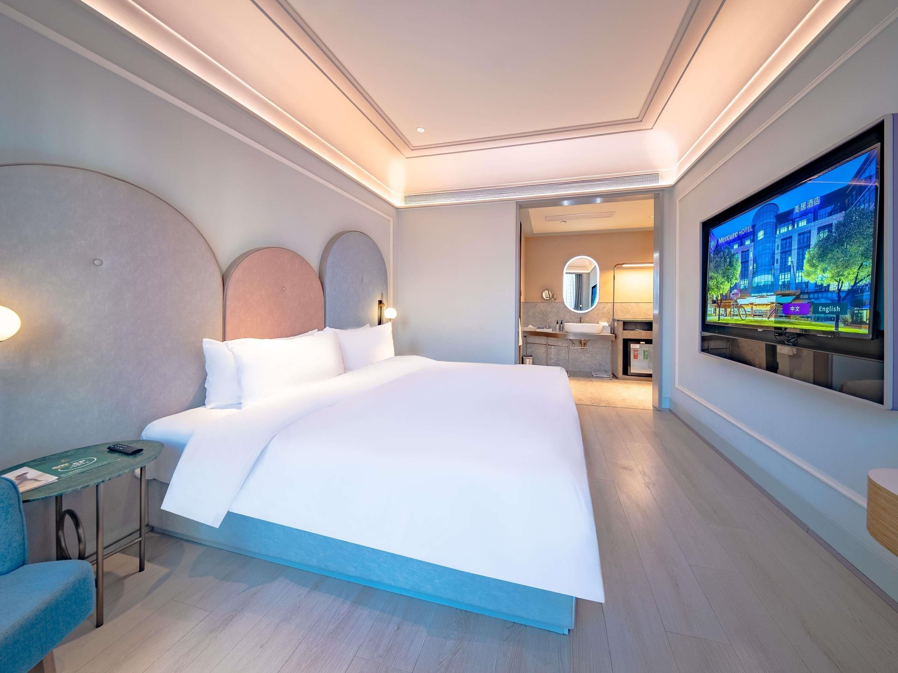 Una habitación de hotel moderna con una cama grande, un televisor y un escritorio con una silla.