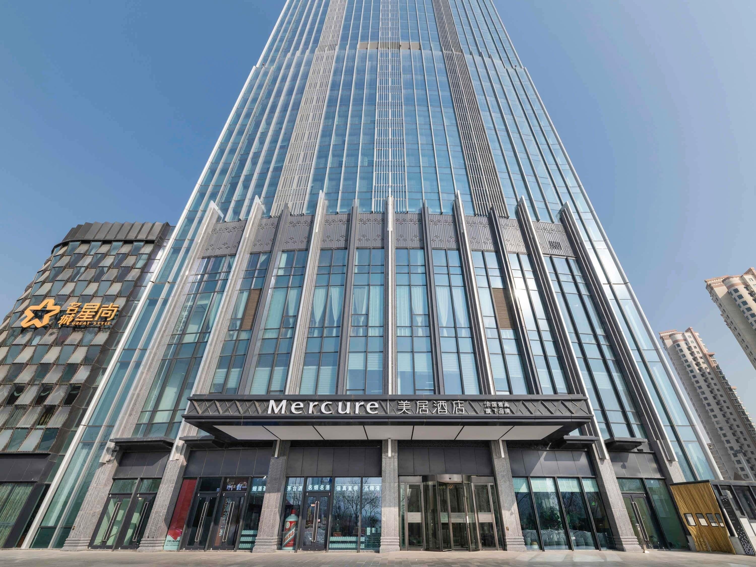 A tall, modern building with a glass facade and a prominent entrance.