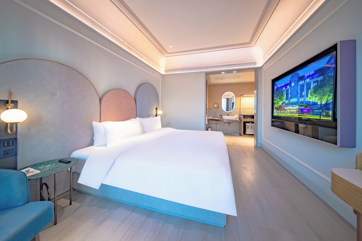 Una habitación de hotel moderna con una cama grande, televisión, escritorio y una silla.