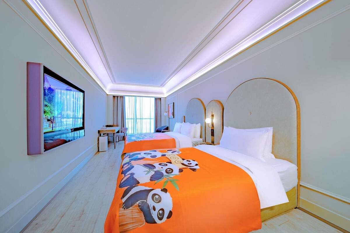 A hotel room with a bed, a desk, and a TV mounted on the wall.