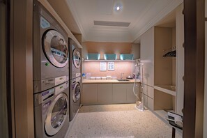 Un cuarto de lavandería con dos lavadoras, un lavamanos y un espejo.
