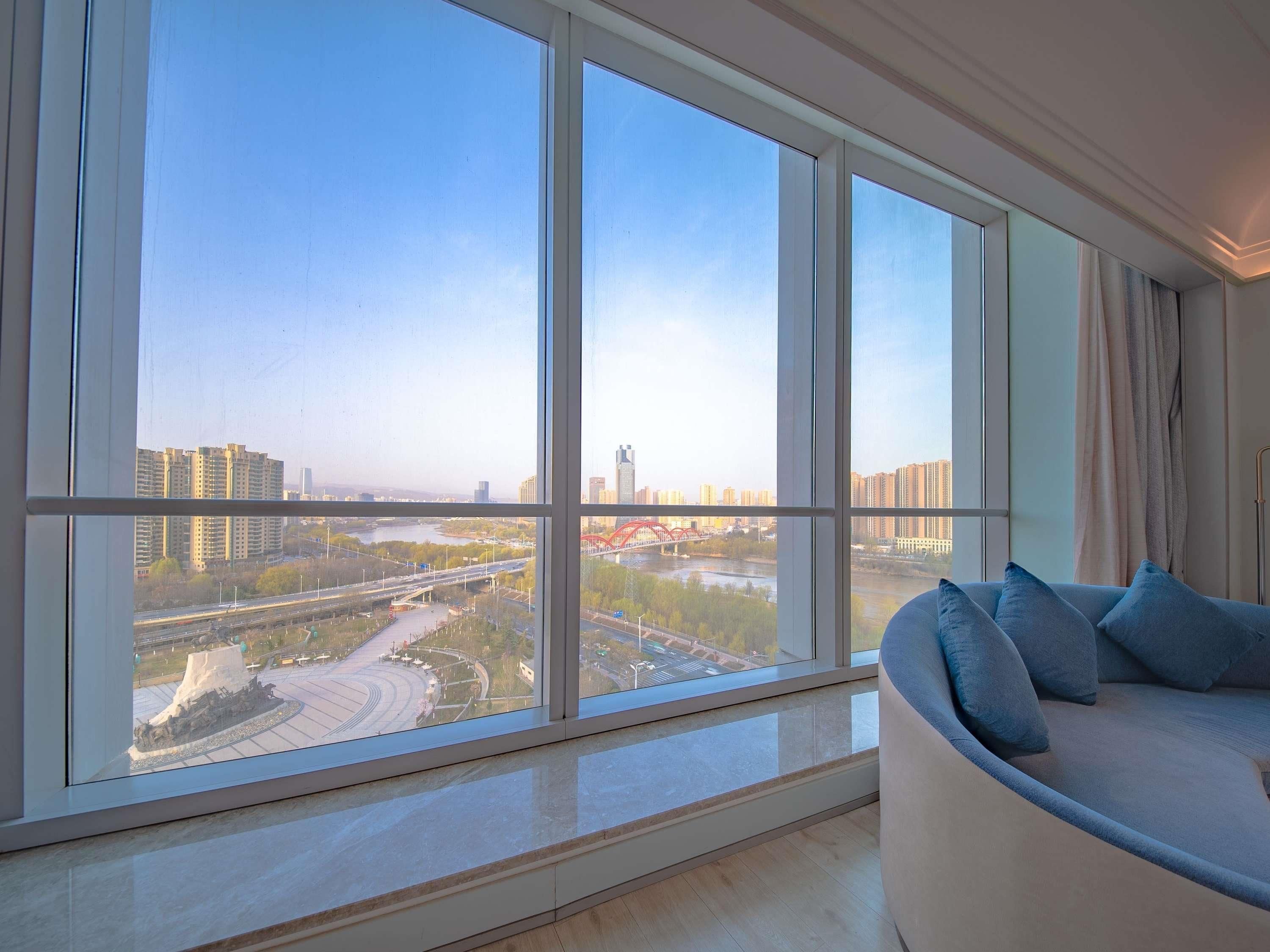 Een moderne woonkamer met een groot raam dat uitzicht biedt op een stadsgezicht en een rivier.