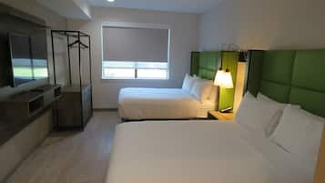 Habitación de hotel con dos camas, televisión, ventana y cabecera verde.