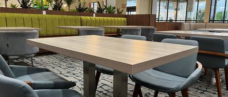 A modern hotel lobby with a large seating area, a reception desk, and a view of the outside through large windows.
